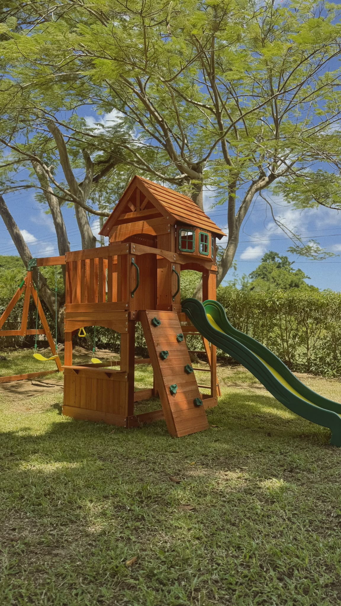 Bambini’s outdoor play structure and slide beneath leafy trees in the garden
